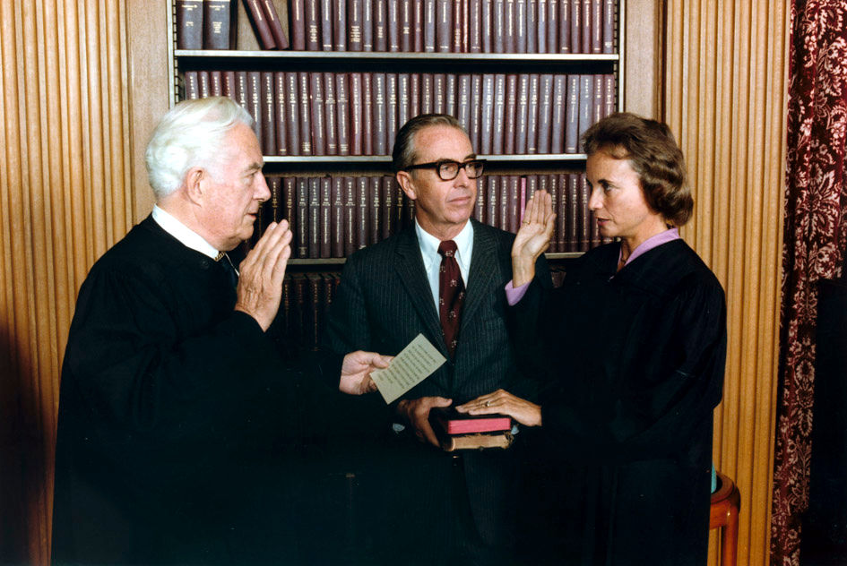 Sandra Day O'Connor being sworn in in front of two people and books