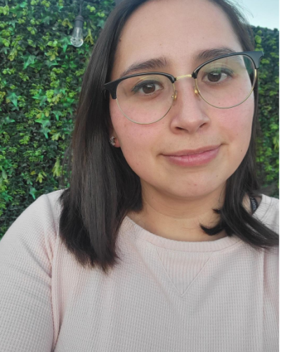 Alondra Salazar wearing glasses with greenery in background
