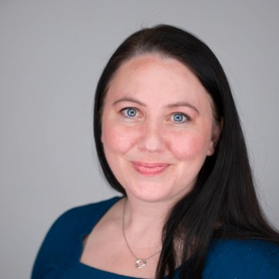 Portrait of woman with dark hair, necklace and blue shirt