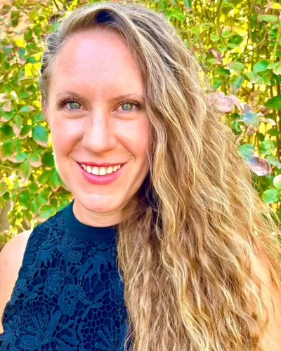 Tara Bartlett portrait photo, smiling with greenery in background